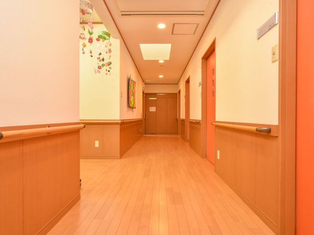 温かみのある廊下の風景 廊下 手すりがあり安全に配慮された明るい廊下です。壁に飾られたアートが活気を与えています。