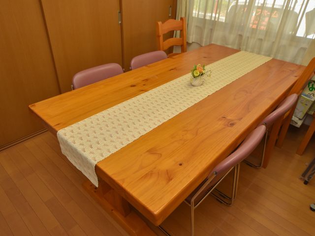 明るい食堂のテーブルセット 談話室 落ち着いた色合いの木製テーブルが置かれ、居心地の良い空間が広がっています。
