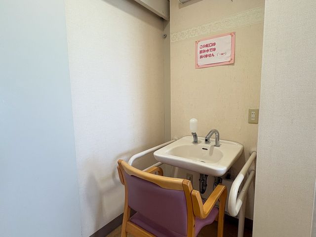 手洗い用洗面台 洗面台   手すりが付いた洗面台と椅子があり、座ったまま使いやすそうです。壁には飲み水ではない旨の掲示があり、案内がわかりやすいです。