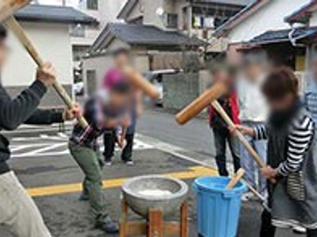 屋外で餅つきをする人々の様子 中庭 広々とした屋外のスペースで、楽しく餅つきをしているシーンです。チームワークとコミュニケーションが自然に生まれる場です。