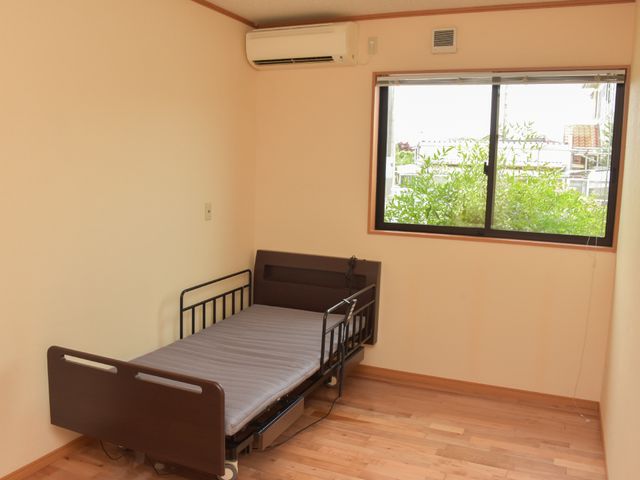 居室内のベッドと窓 居室 広々とした部屋には、使いやすい電動ベッドが配置され、窓からは自然光が差し込んでいます。