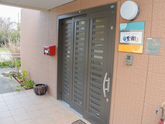 出入口のモダンな扉 玄関 手すり付きの安全なデザインの入口です。車椅子でも安心して出入りできる造りになっており、働く環境も配慮が行き届いています。