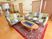 サムネイル 赤い絨毯の上にテーブルと、カラフルな大きなソファが２つ置かれている。背後には居室のドアが並び、手すりの設置された壁がある。