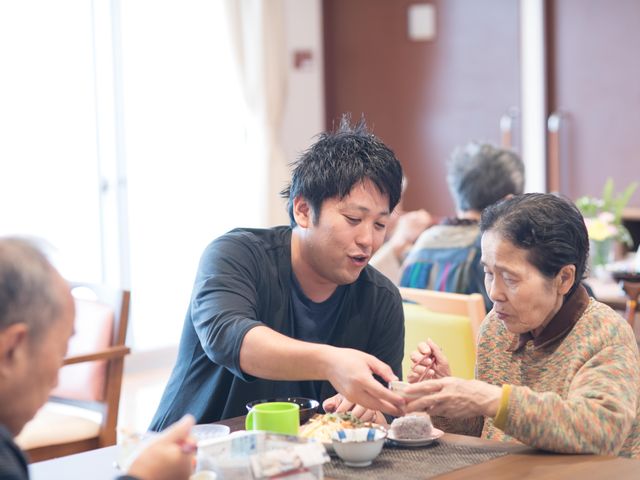 食事支援をするスタッフ スタッフが優しく食事のお手伝いをしている温かい雰囲気の食堂です。みなさんリラックスしてお食事をされています。