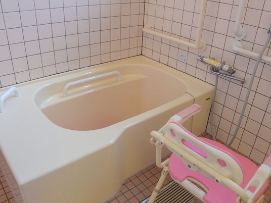 タイル張りの浴室に小さめのバスタブがあり、内側や壁に手すりが付いており安全である。シャワーチェアーが置いてある。