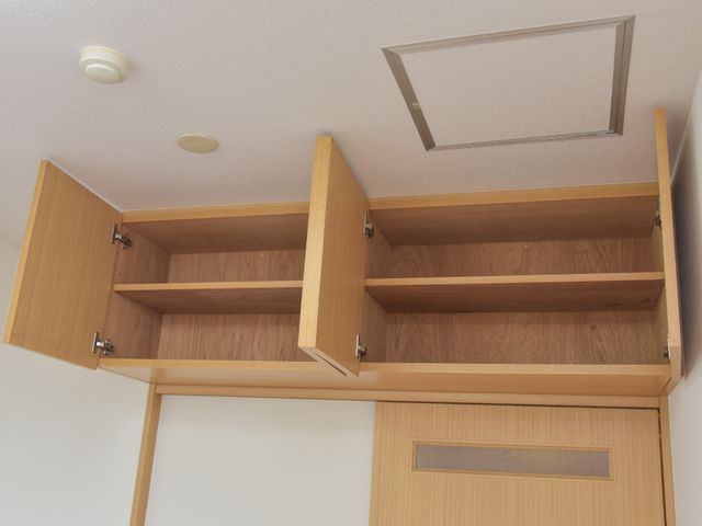 木製の開いた扉付き収納 収納 天井に近い位置に設けられた木製クローゼットは、開いた扉から広々とした収納スペースを確認でき、日々の生活で大切な物品を整理しておくのに適しています。