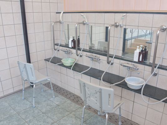 シャワーと鏡が横並びに備え付けられている。その手前には介護用椅子があるので無理なく髪や身体を洗うことができる。鏡付近には手すりがついている。