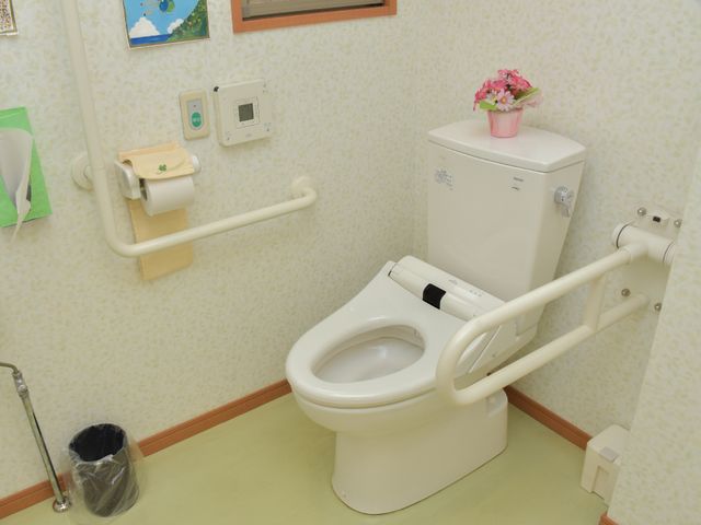 バリアフリートイレ設備 トイレ 安心してご利用いただける、握りやすい手すり付きのトイレです。お花が飾られ、温かみのある空間づくりがされています。