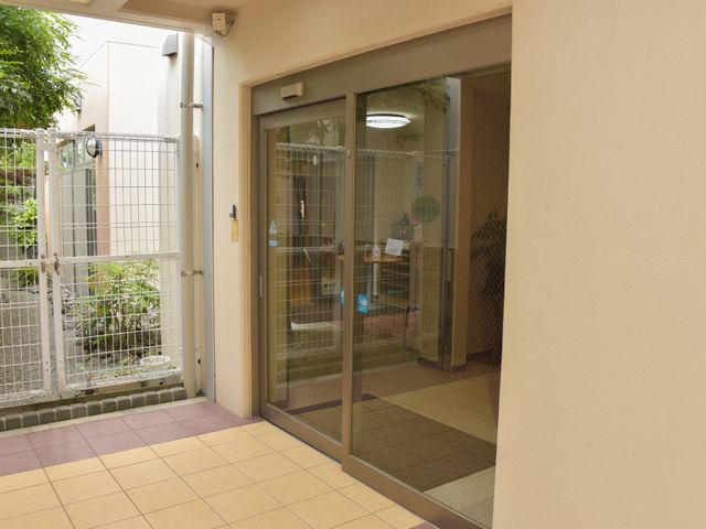 ガラス扉の開放的なエントランス 入り口 ゆったりとしたエントランスは、訪れる人を明るく迎え入れる雰囲気です。手すりも備えたバリアフリー設計で、安心して出入りできます。