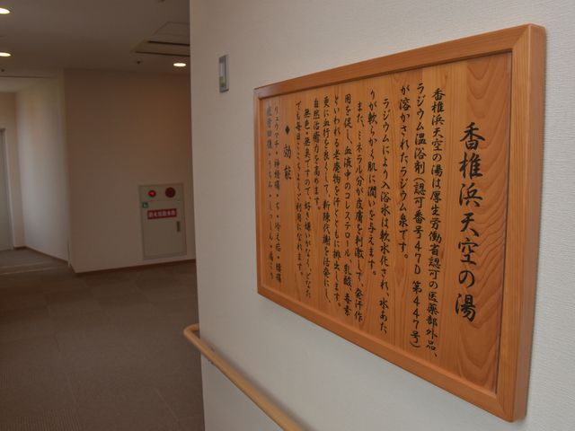廊下に掲示された木製看板 展望浴場「スカイスパ」 温かみのある木製の看板が廊下に掲示され、訪れる人々に優しい気持ちを与えています。読むことで施設の理念が伝わり、職員としての使命感を感じられるでしょう。