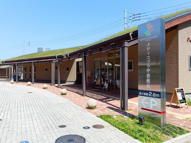 エントランス看板の風景 メディコプラザ香椎浜 草生す屋根が印象的な入口です。温もりを感じるデザインが、訪れる皆さまをやさしくお迎えします。