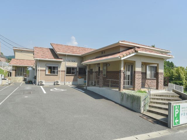 日差しが降り注ぐ施設外観 施設外観 清潔感のある広々とした駐車場が迎える落ち着いた風貌の建物です。