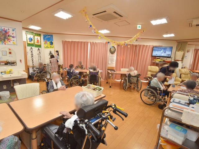 活気ある共有スペース 食堂兼居間 明るい装飾が施され、利用者同士が親しく交流している様子が見受けられます。