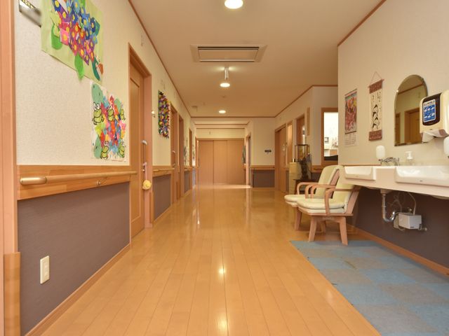 明るい廊下の風景 廊下 色とりどりの壁飾りが廊下に暖かみを加え、待合の椅子があります。