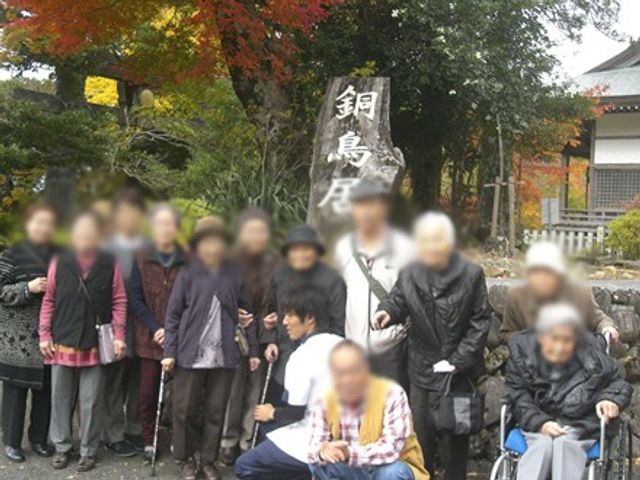 外で団体が集まる様子 庭 にぎやかな庭で、皆さんが集まって楽しそうに過ごしています。自然に囲まれたリラックスした環境です。