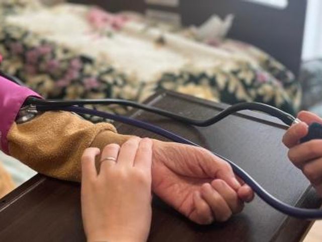 血圧を測る手のぬくもり 機能訓練室 丁寧な手つきで血圧測定を行う風景です。安心してご利用いただける空間が整っております。