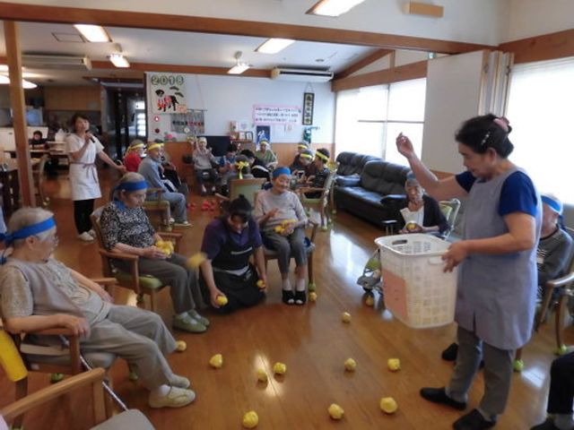 活動中の居室 レクリエーション 広々とした居室で、皆がリング投げを楽しむ様子が伺えます。助け合いながら活動する姿は、明るい職場の雰囲気をうかがわせます。