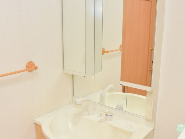 洗面台と鏡のセット 洗面化粧台 手すり付きで利用しやすい洗面台の様子です。清潔感のある明るい空間で、毎日の身支度を快適に行えます。