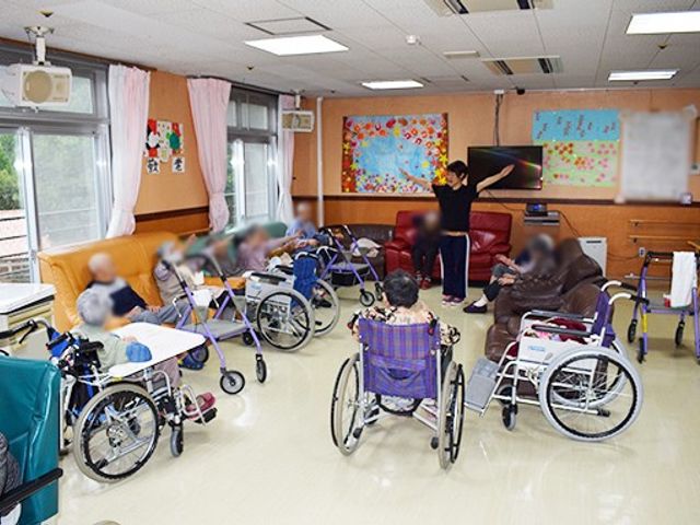 車椅子の人々が集う部屋 ラウンジ 広々とした空間で、車椅子の方々がリラックスして活動を楽しんでいます。自然光が差し込み、和やかな雰囲気です。