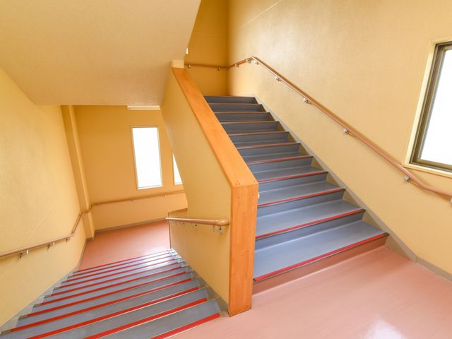 明るい階段廊下 階段 手すりが設けられ、段差のわかりやすい色合いの階段です。安全に移動できる環境が整っています。