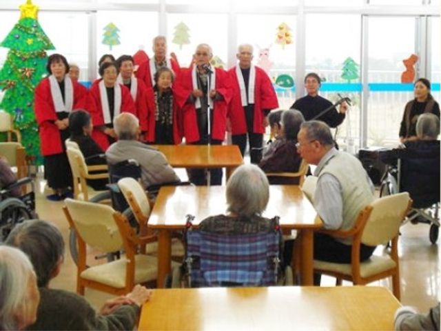 イベントで楽しむ利用者様 クリスマス会 笑顔で集う明るい食堂で、入居者の方々がイベントを楽しんでいます。演奏や歌に合わせて心地よいひと時を過ごせる空間です。