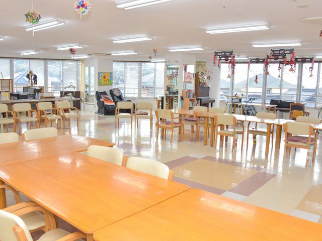明るい共有ダイニングスペース 大部屋 広々としたダイニングで、ゆったりとした椅子にくつろぐ方が見えます。共に食事や会話を楽しめる、温かみのある場所です。