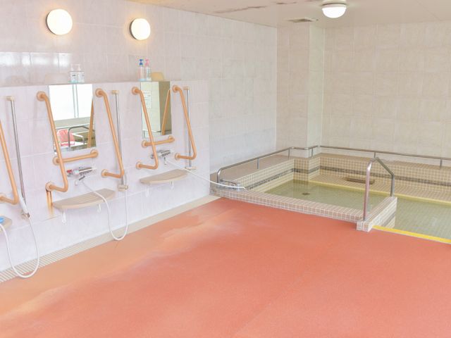 バリアフリー対応の浴室 浴場 安全な入浴をサポートする設備が整った浴室です。手すりやシートが付いており、利用者の方々の快適さを考慮しています。