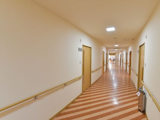 白色の天井と壁に茶色とベージュ色のボーダーの床である。緩やかなカーブを描いた廊下スペースで、壁際には手すりを取り付けている。