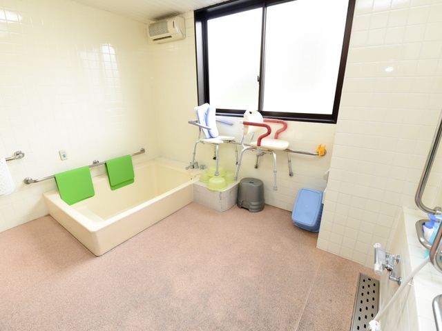 バリアフリー設計の浴室 浴室 手すりや椅子が設置された広々とした清潔な浴室です。利用者の快適さと安全が考慮されたつくりになっており、働く環境としても安心です。