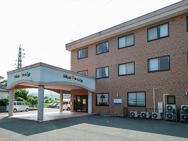 建物正面の外観 外観   三階建ての落ち着いた外観で、車寄せ付きの出入口が見えます。駐車スペースもあり、送迎時の動線をイメージしやすいです。