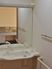 サムネイル 施設の写真 前面に大きい鏡が設置されている機能的な洗面台。幅の広い洗面台にはシャワー切り替え式蛇口が取り付けられている。