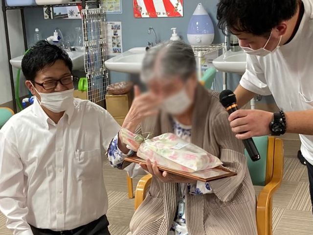 笑顔の交流が見られる室内 内観 明るい空間でスタッフが利用者と親しく交流する場面です。安心して働ける環境が整っています。