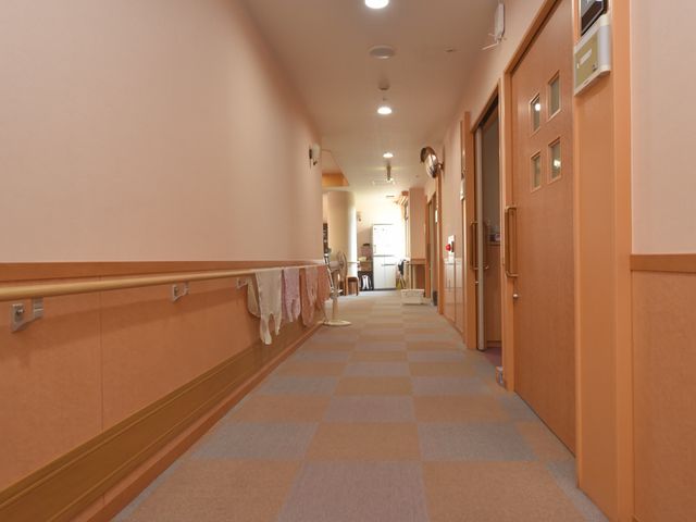 廊下の静かな様子 通路 ゆったりとした廊下は手すりが整備され、清潔で明るい雰囲気が漂っています。動線に配慮された設計で、快適にお過ごしいただける空間です。