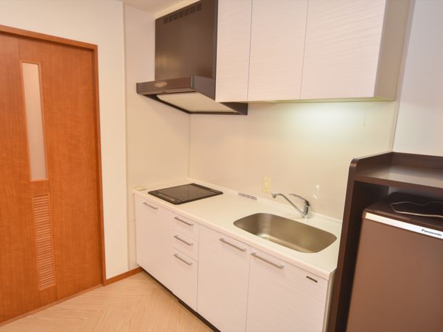 整った小規模キッチン 居室 コンパクトで清潔感のあるキッチンは、日々の料理を快適に支援します。必要な設備が整い、自立生活をサポートしています。