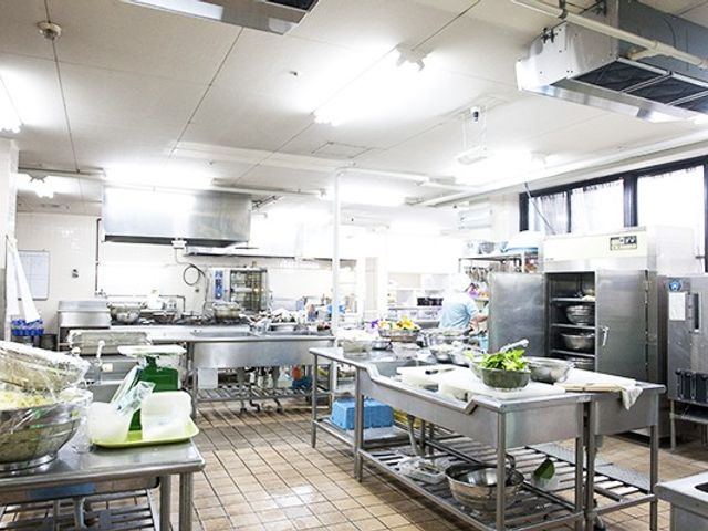 広々とした清潔なキッチン キッチン 広々と整備されたキッチンでは、食事の準備に携わるスタッフの姿が見られ、清潔感が漂っています。