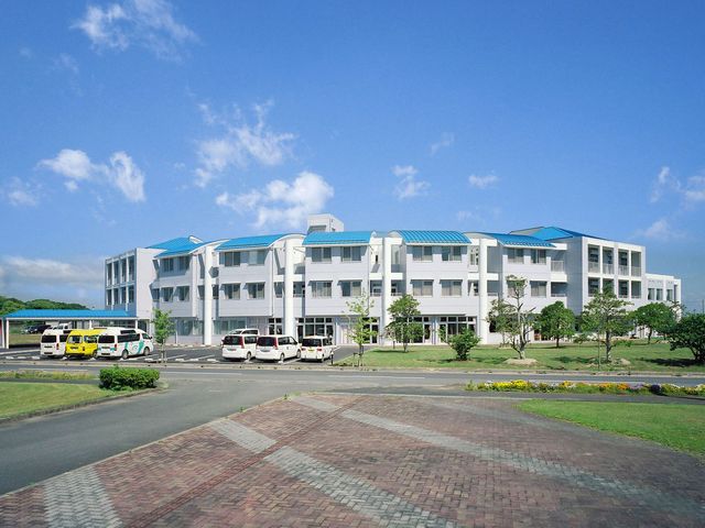 青空のもとに立つ建物 外観 広々とした施設は、自然環境にも恵まれています。周囲には緑が豊富で働く環境としても魅力的です。