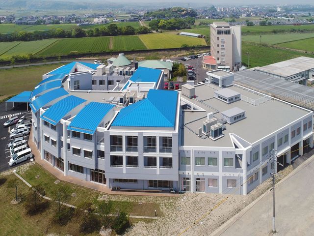 白い外観の建物 外観 青い屋根と広大な敷地が特徴の建物です。周りには豊かな自然が広がっています。