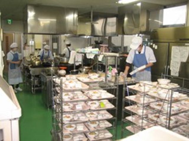 調理を行う厨房 キッチン 清潔で効率的なキッチンで、スタッフが献立に沿った料理を準備しています。手際よく作業できる環境です。