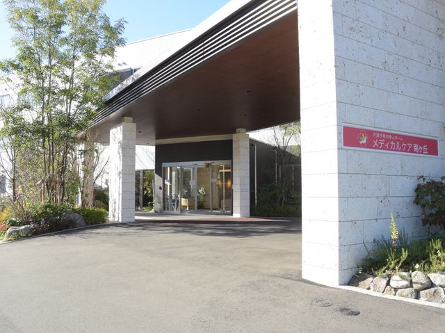 エントランスと庭園 玄関 開放的なエントランスがお出迎えします。自然に囲まれた明るい通路が、利用者様の安らぎの空間を提供します。