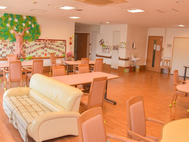 暖かみのある広々とした食堂 共有スペース3 ゆったりとしたソファが置かれた食堂では、利用者が心地よい時間を過ごしている様子が伝わります。壁には季節感のあふれるデコレーションも施され、居心地の良い環境が整っています。