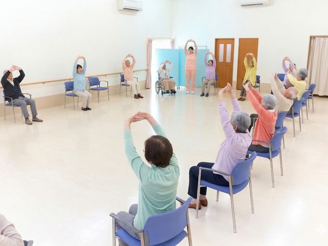 体操が行われている部屋 機能訓練室 広々とした明るいスペースでの体操活動です。車椅子の方も安心して参加できる環境です。