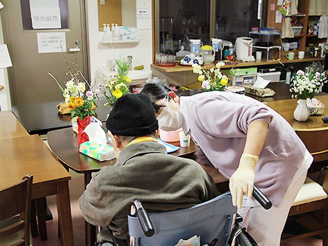 ケアスタッフと利用者の様子 居室 優しい手つきで支援するスタッフが寄り添い、穏やかな雰囲気の中で日々の生活をサポートしています。