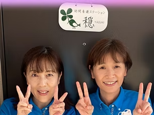 笑顔のスタッフ2人が並ぶ看板前  