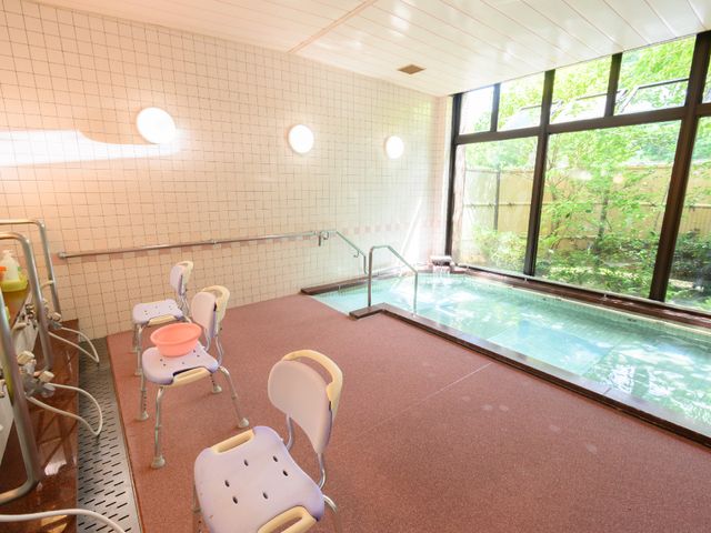明るい手入れの行き届いた浴室 大浴場 透明な窓から自然光が差し込む、ゆったりとした浴室です。支援用の椅子も用意され、安心してご利用いただけます。