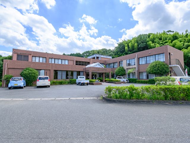 広々とした緑豊かな外観 スタッフ 緑に囲まれた落ち着いた雰囲気の建物です。来訪者を迎える広い駐車スペースがございます。