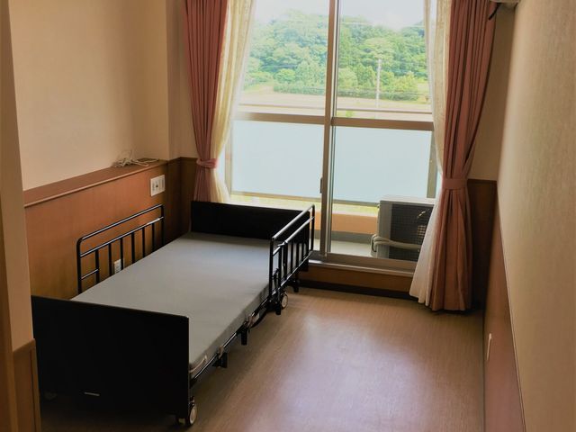 ベッドと窓の居室 居室 広々としたスペースに自然光が差し込む明るい居室です。快適な環境でリラックスできます。