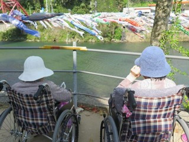川沿いの背中を見せる車椅子 庭 川の景色を楽しむことができる庭。リラックスした雰囲気で、心の安らぎを提供します。