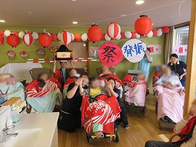 和やかな祭りの様子 多目的室 和やかなお祭りの雰囲気が漂う空間で、皆さんが楽しそうに参加されています。カラフルな装飾が印象的です。