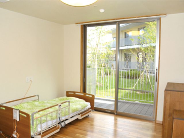 明るい居室とベッド 居室 ゆとりのある居室には、窓から自然光が差し込み、明るい雰囲気を醸し出しています。ベッド周辺も広々としており、快適な生活空間を提供しています。