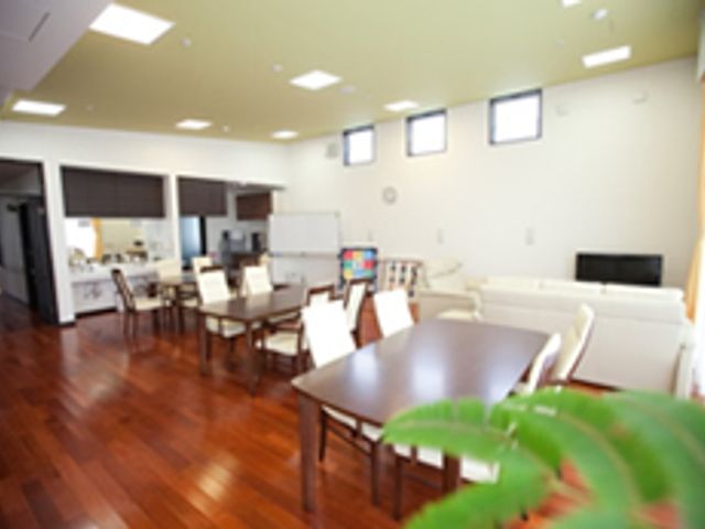 広々としたリビング リビング 自然光が差し込む開放的な空間で、入居者が快適に過ごせます。テーブルやソファが配置されています。
